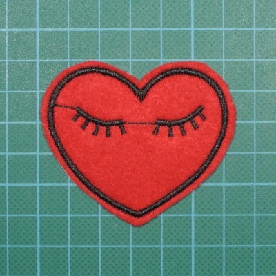 Patch em forma de coração vermelho com olhos fechados desenhados em preto