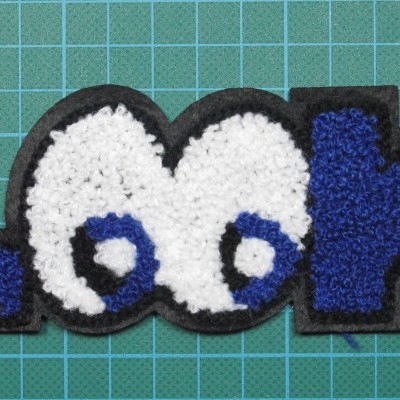 Emblema de tecido com a palavra 'Look' em azul e branco sobre fundo preto