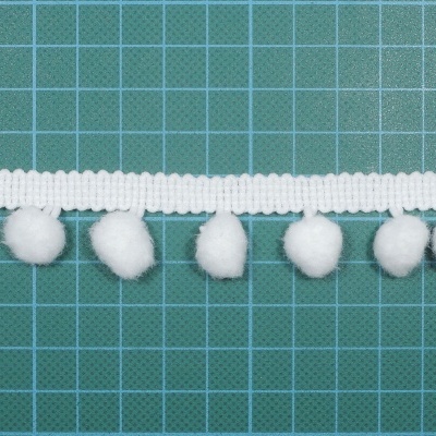 Fita branca com pompons de algodão sobre fundo quadriculado verde