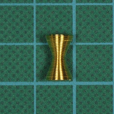 Peça metálica dourada cônica dupla com estrias sobre base verde e grelha azul