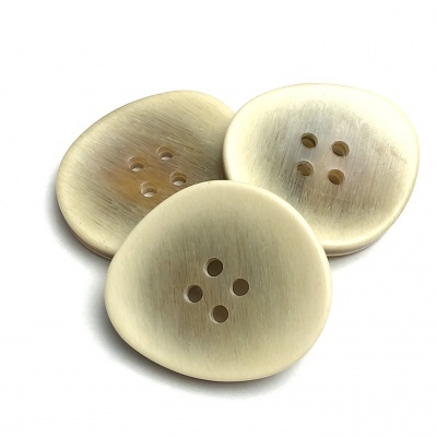 Três botões bege claro com quatro furos sobre fundo branco