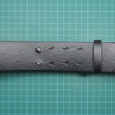 Cinto preto de couro sobre fundo verde quadriculado