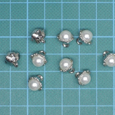 Pendentes com pérolas brancas e metal prateado em superfície de grelha azul