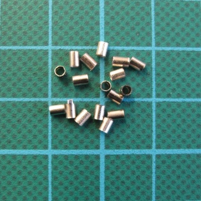 Pequenos cilindros metálicos dourados sobre fundo verde com grelha azul