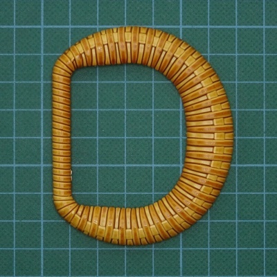 Alça de cesto em madeira formato D sobre superfície verde quadriculada