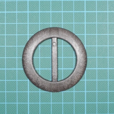 fivela redonda em metal cinza escuro sobre fundo com grelha azul claro