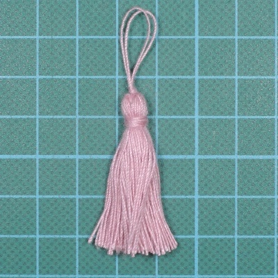 Borla pequena cor de rosa com laço em fundo quadriculado verde