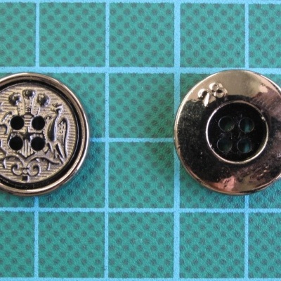 Dois botões metálicos prateados sobre superfície quadriculada verde