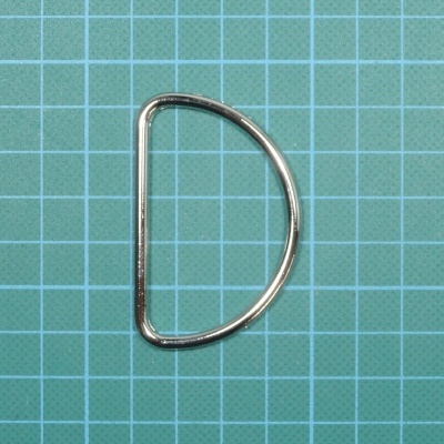 Argola metálica em forma de D sobre superfície verde quadriculada