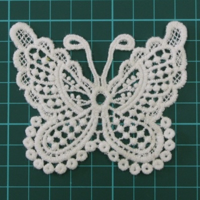 Renda branca em forma de borboleta sobre fundo verde quadriculado