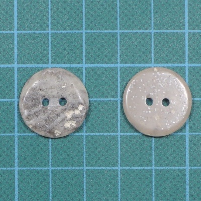 dois botões redondos com dois furos sobre superfície azul com padrão de grade