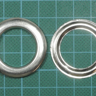 Dois ilhós metálicos prateados sobre base verde quadriculada