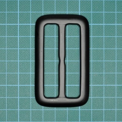 Fivela ou passador rectangular preto sobre fundo quadriculado verde