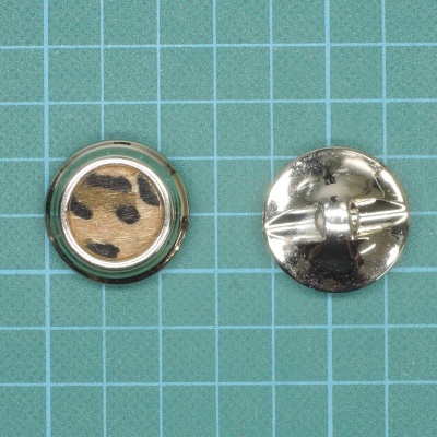 Botões metálicos redondos com padrão de pele animal em fundo de grelha verde