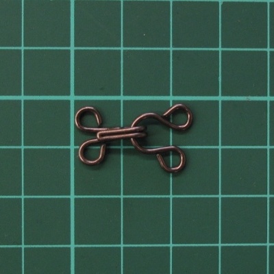 Fecho de sutiã em metal escuro sobre superfície verde quadriculada