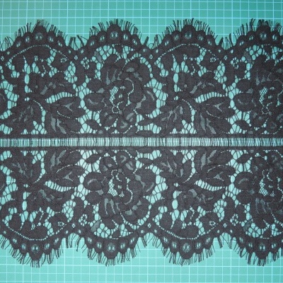 Renda preta floral com borda ondulada e franjas sobre fundo verde de grelha