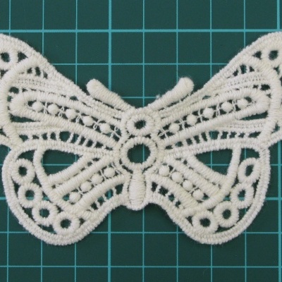 Aplicação de renda branca em forma de borboleta sobre superfície verde quadriculada