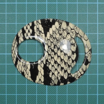 Objeto oval com padrão de pele de cobra sobre superfície verde quadriculada