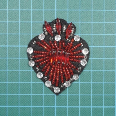 Aplicação decorativa com contas vermelhas e prateadas sobre base preta