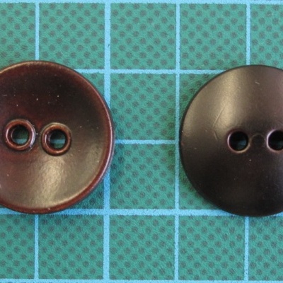 Dois botões redondos castanhos sobre superfície quadriculada verde