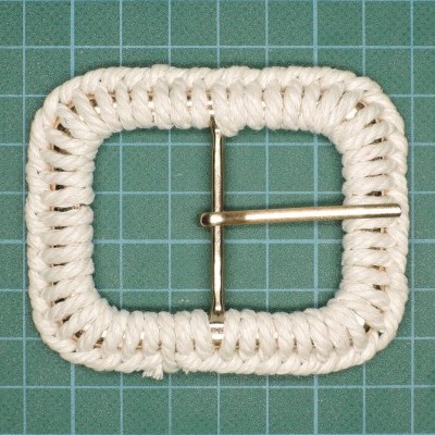 Fivela quadrada branca revestida com corda e asa metálica dourada.