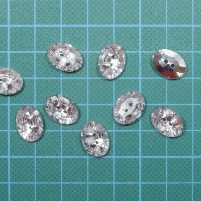 Botões ovais prateados com textura facetada sobre fundo quadriculado azul