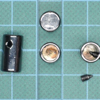 Peças metálicas pequenas e parafuso sobre superfície quadriculada azul