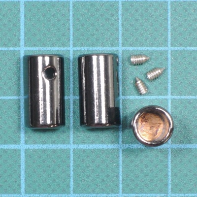 Peças metálicas cilíndricas e parafusos pequenos sobre matriz verde quadriculada