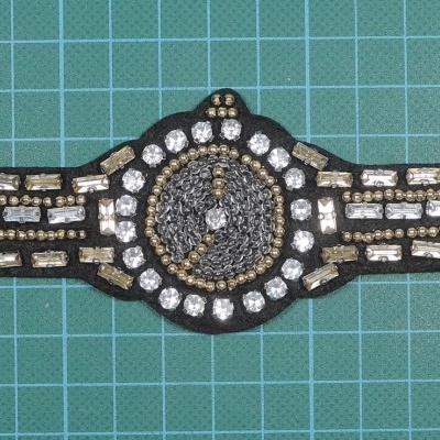 Peça decorativa de tecido preta com pedras brilhantes em padrão geométrico