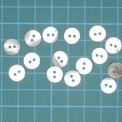 Botões brancos redondos com dois buracos sobre superfície azul quadriculada