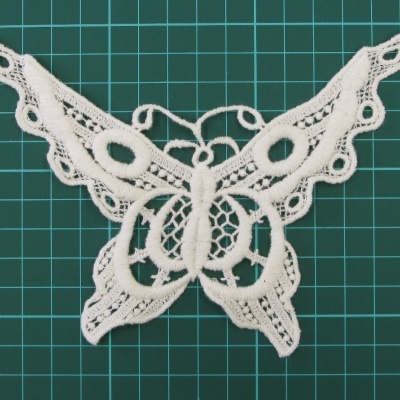 Aplicação em renda branca em forma de borboleta sobre fundo verde de grade