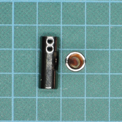 Peças metálicas cilíndricas pequenas sobre grelha azul com quadrados brancos