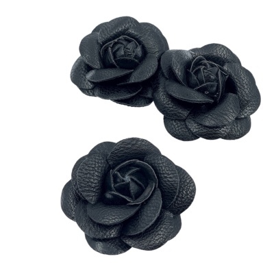 Três flores pretas de couro texturizado em fundo branco