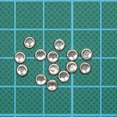 Pequenas peças metálicas redondas com interior côncavo em superfície azul quadriculada