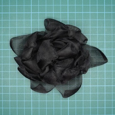 Flor decorativa preta em tecido translúcido sobre fundo quadriculado verde