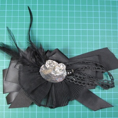 Acessório decorativo preto com plumas e aplicação prateada