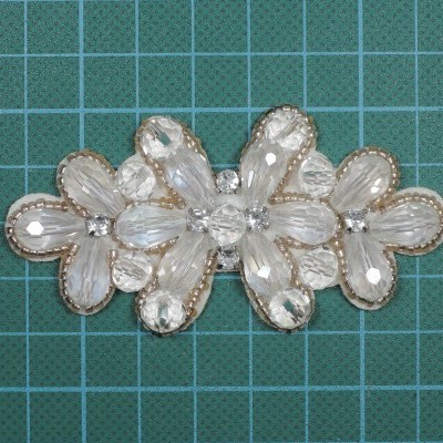 Aplicação decorativa floral com contas transparentes sobre superfície quadriculada verde