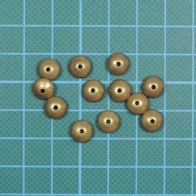 Dez conta redondas douradas com furos sobre superfície quadriculada azul e verde