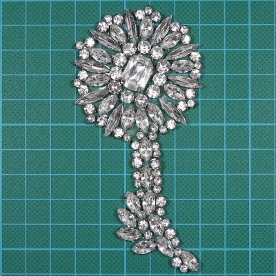 Broche de bijuteria com pedras transparentes sobre fundo de grade azul esverdeada