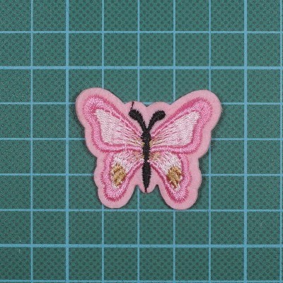 Aplicação bordada de borboleta cor-de-rosa sobre superfície verde quadriculada