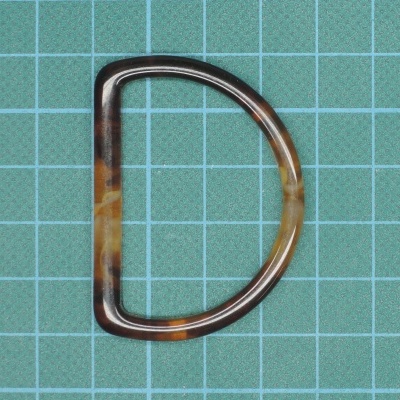 Argola de plástico em forma de D com padrão marmoreado castanho e bege sobre fundo quadriculado verde