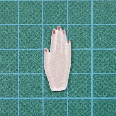 Adesivo em formato de mão feminina de cor clara com unhas vermelhas sobre superfície verde quadriculada