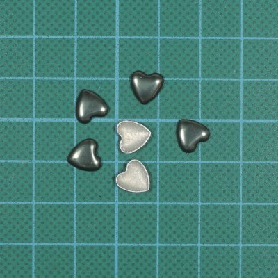 Corações metálicos pretos e prata sobre folha verde com grade azul