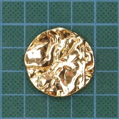 Botão dourado texturado redondo numa grelha verde