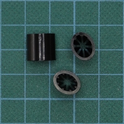 Peças cilíndricas pretas com interior em forma de estrela sobre base verde de grelha
