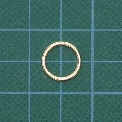 Anel dourado circular sobre superfície verde com grade branca