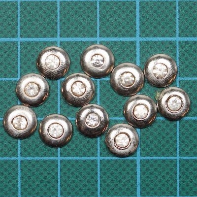 Botões metálicos prateados sobre base quadriculada azul-esverdeada