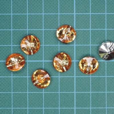 Seis botões redondos em tons laranja e prateado sobre fundo quadriculado verde
