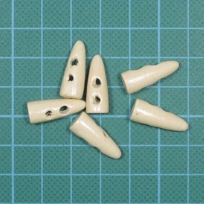 Seis botões de osso claros com orifícios, sobre superfície quadriculada verde