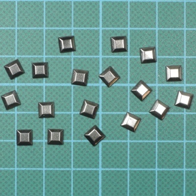 Botões metálicos quadrados prateados sobre fundo quadriculado verde